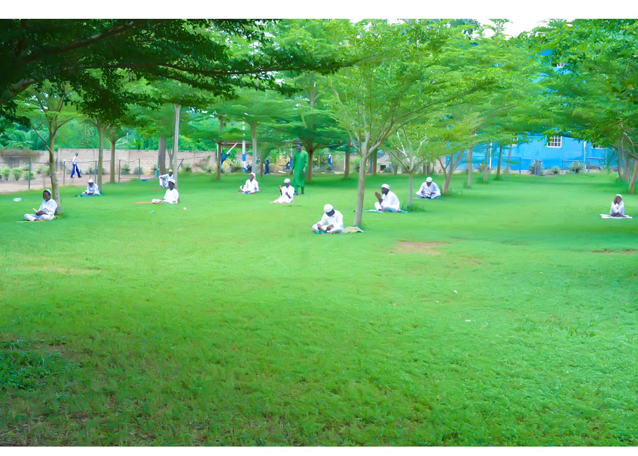 Inaayatullah pupils reading and revising across the green school grounds
