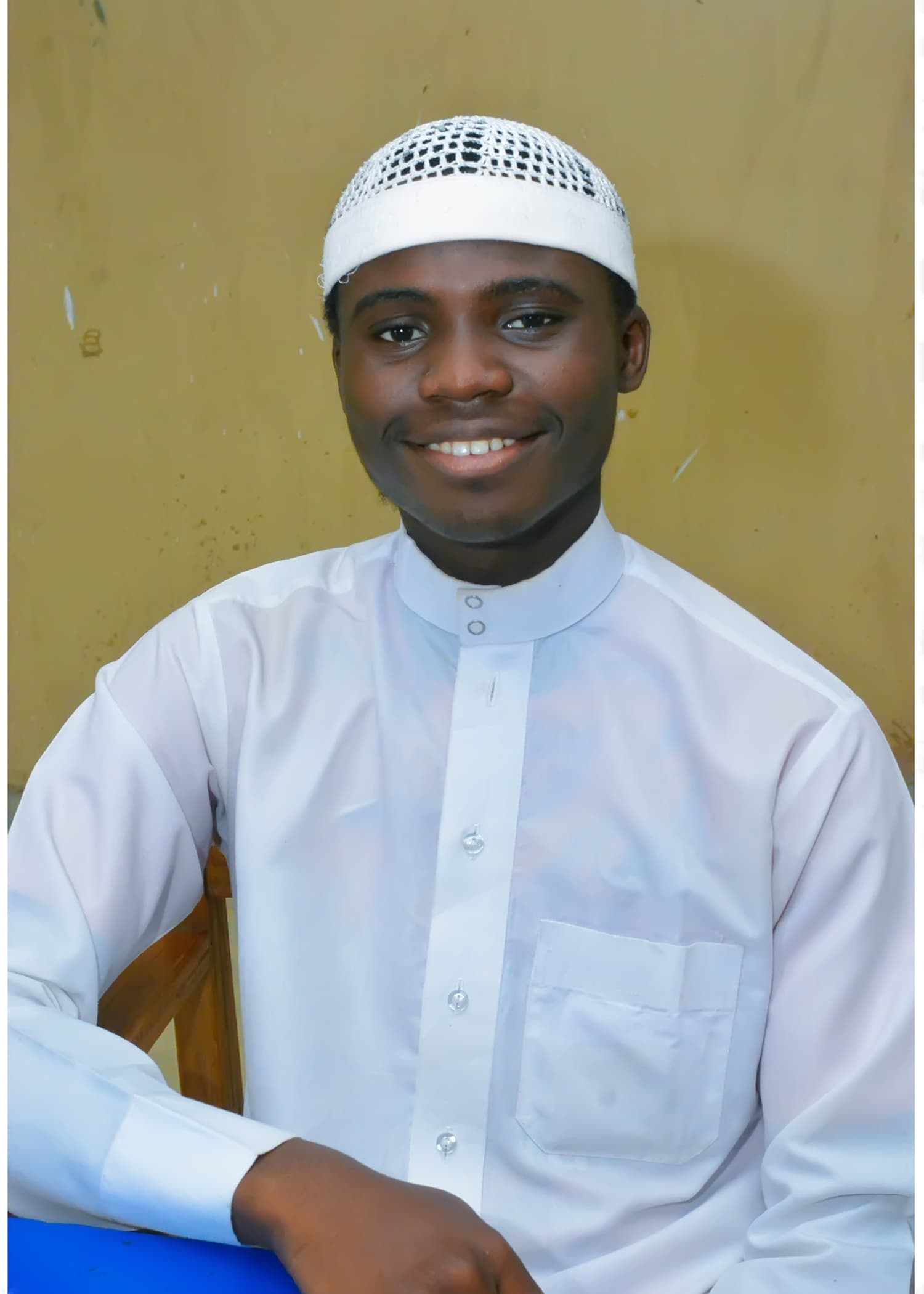A smiling Inaayatullah student wearing white Islamic clothing