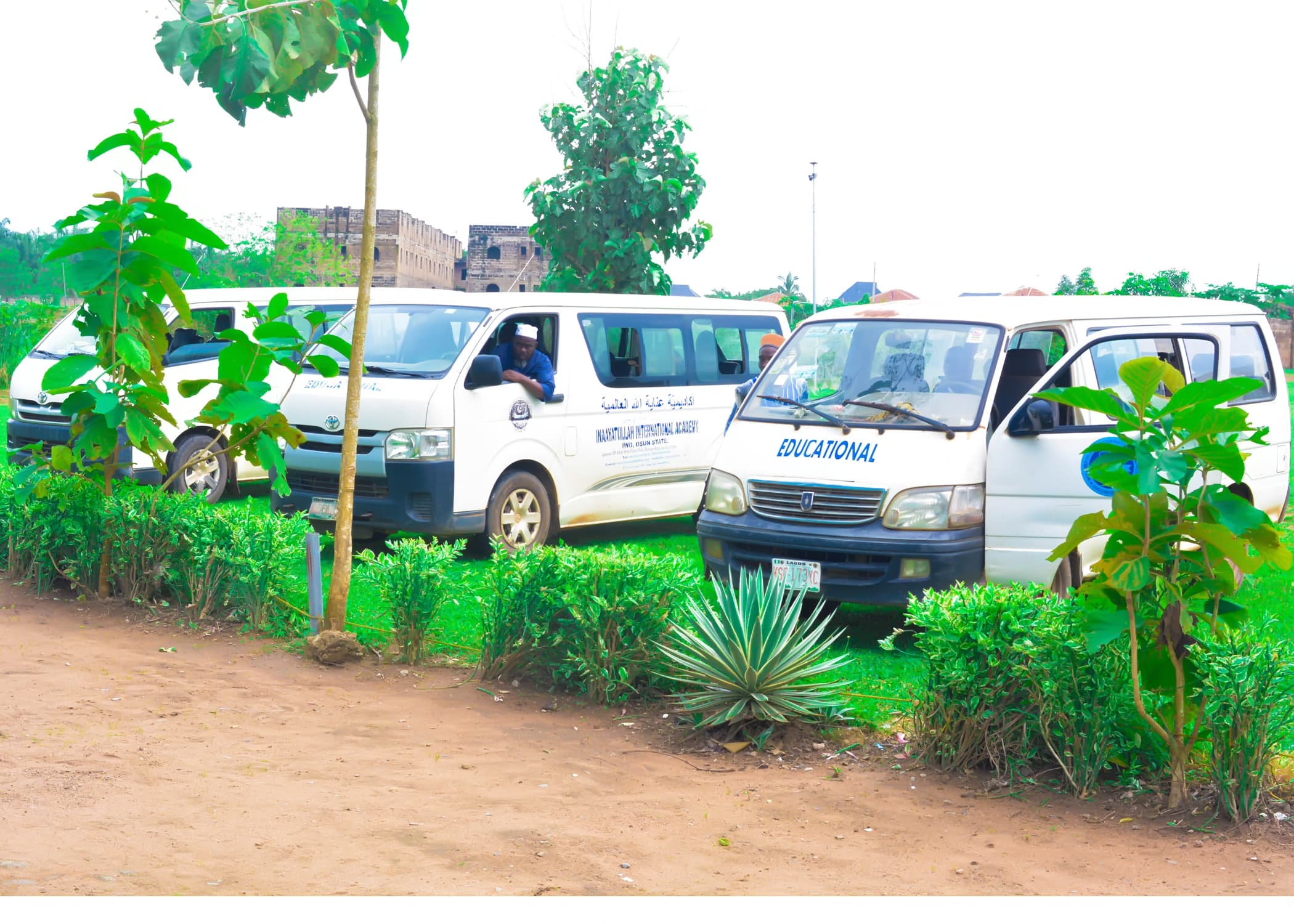 Inaayatullah school buses parked within the landscaped Academy grounds