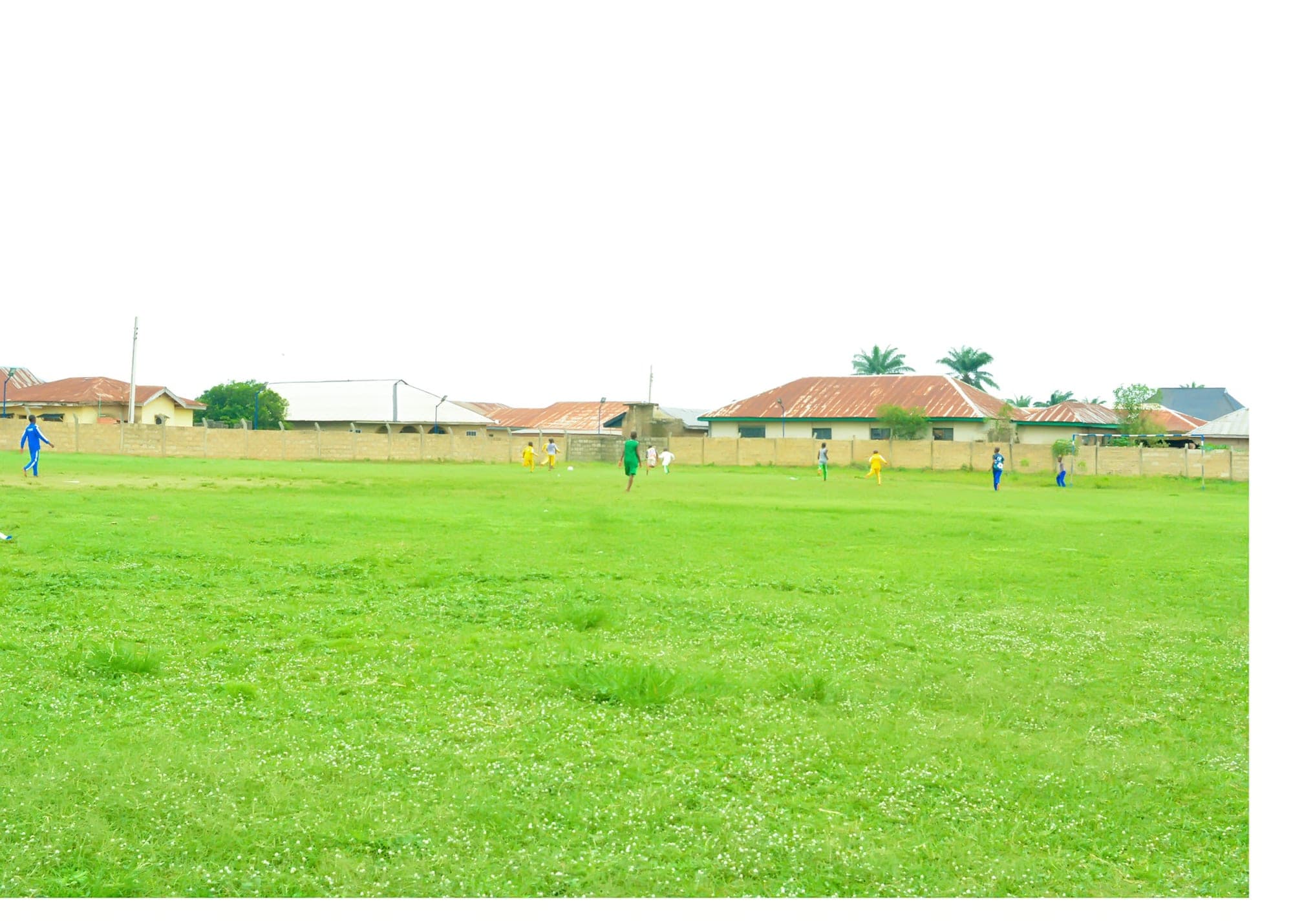 A wide view of pupils playing football on the green school field