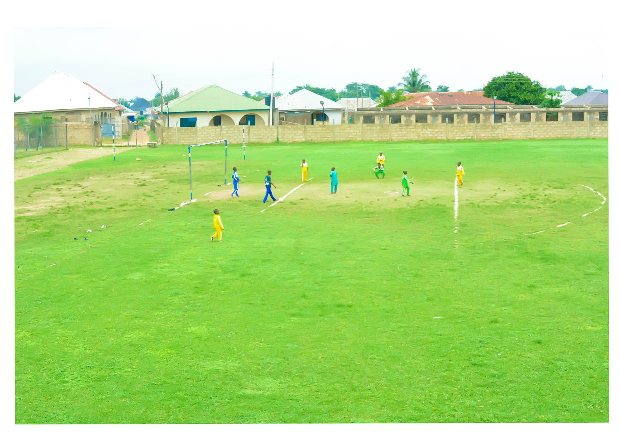 Pupils in bright kits playing football on the school pitch