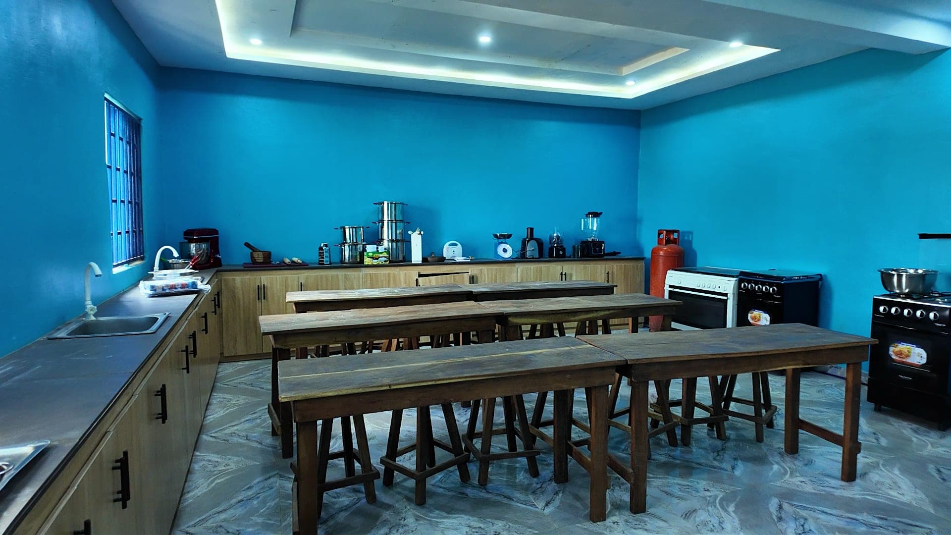 A practical room equipped with a cooker, sink and work tables