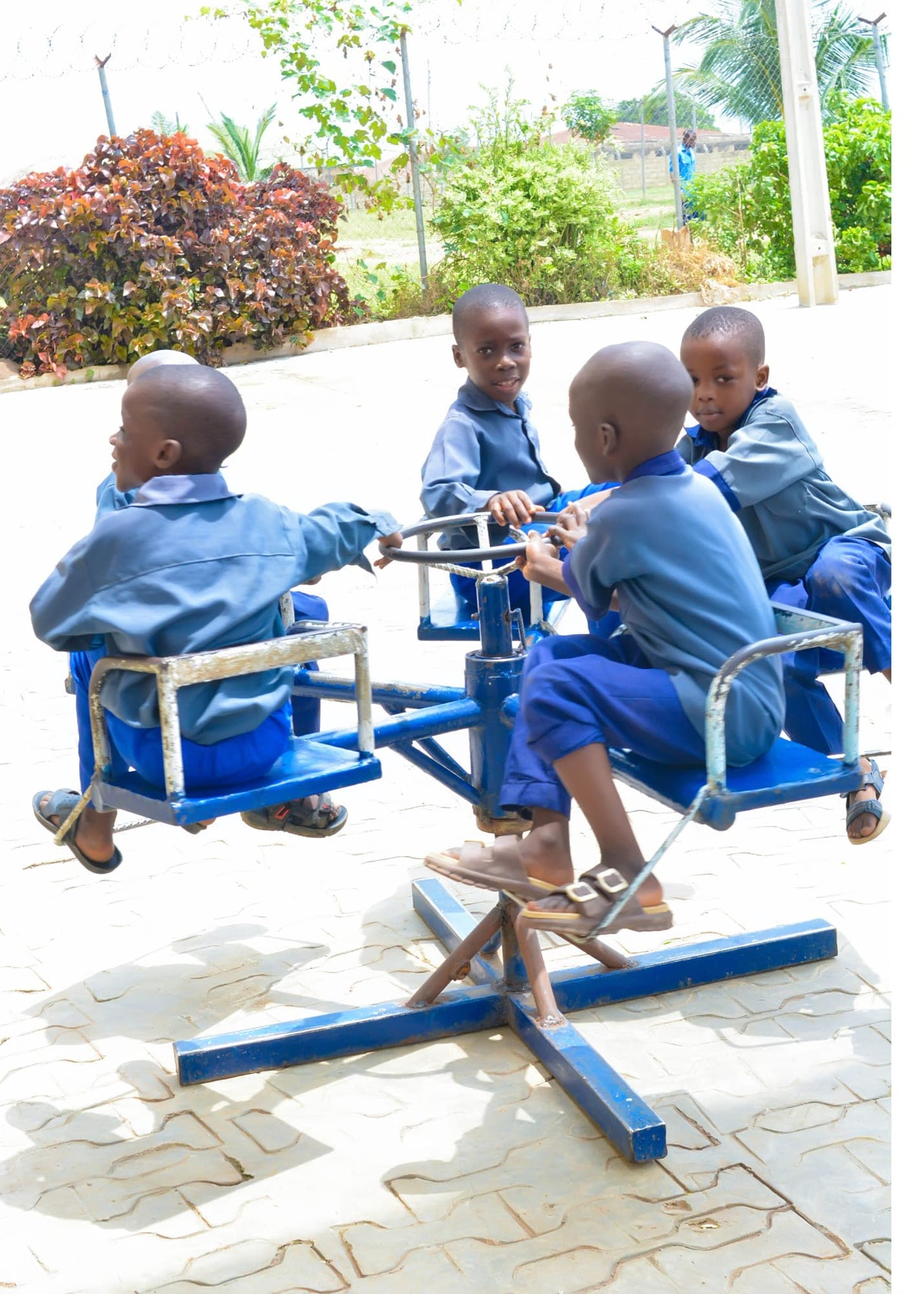 Boys in blue uniforms riding a playground roundabout