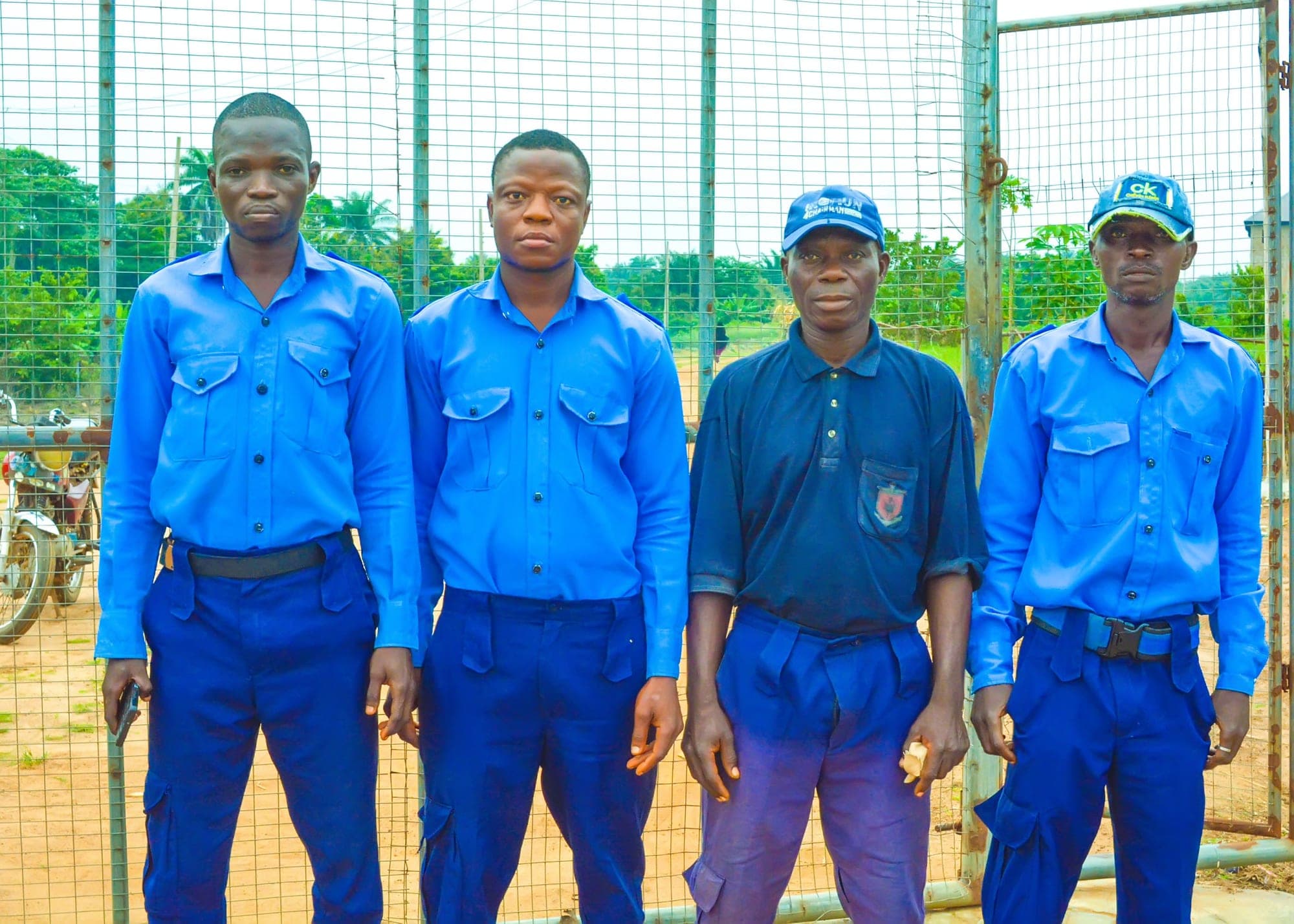 Four members of the security staff in blue uniforms standing together by the sports court
