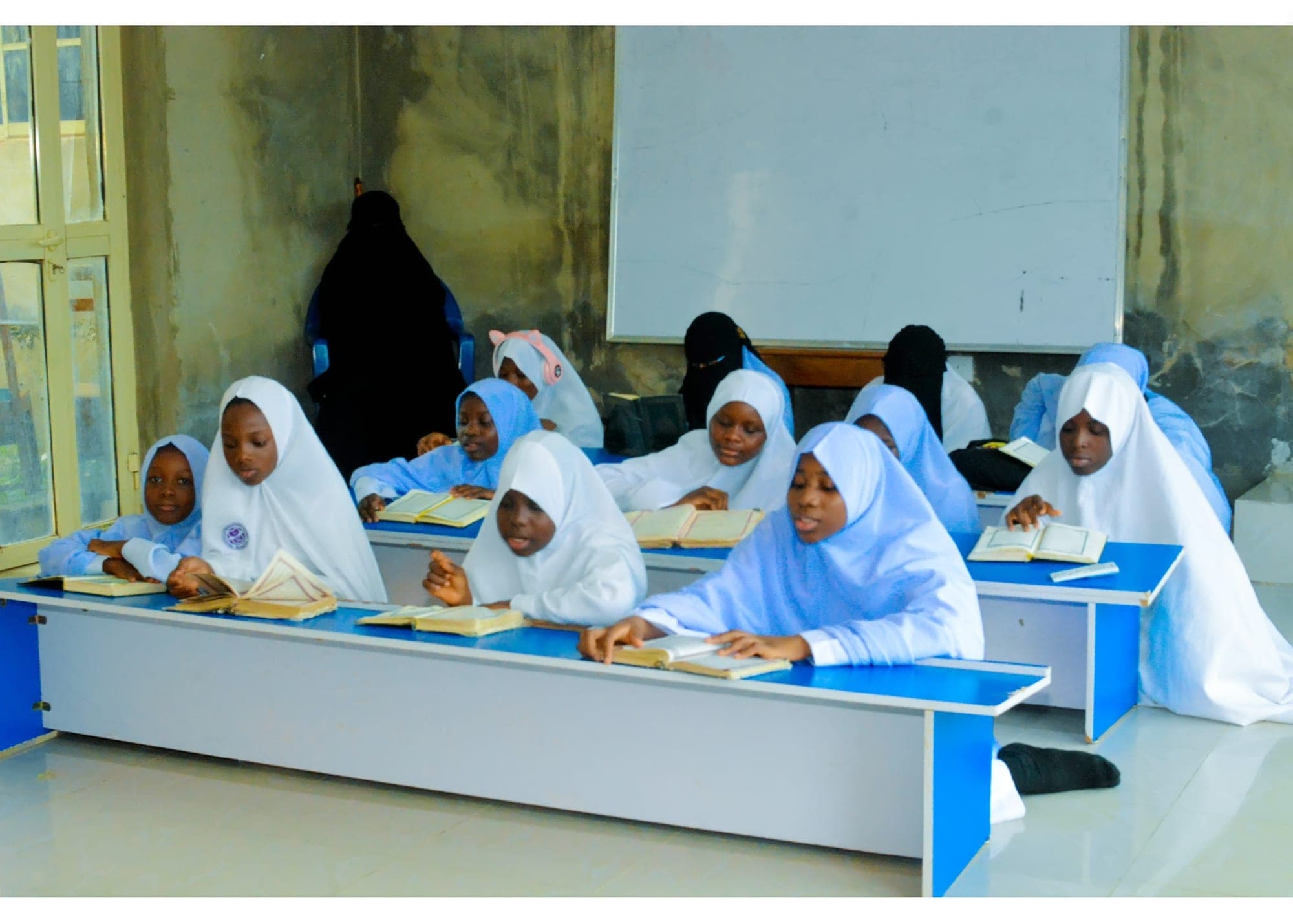 Tahfiz girls in white hijabs reading the Qur’an at their desks