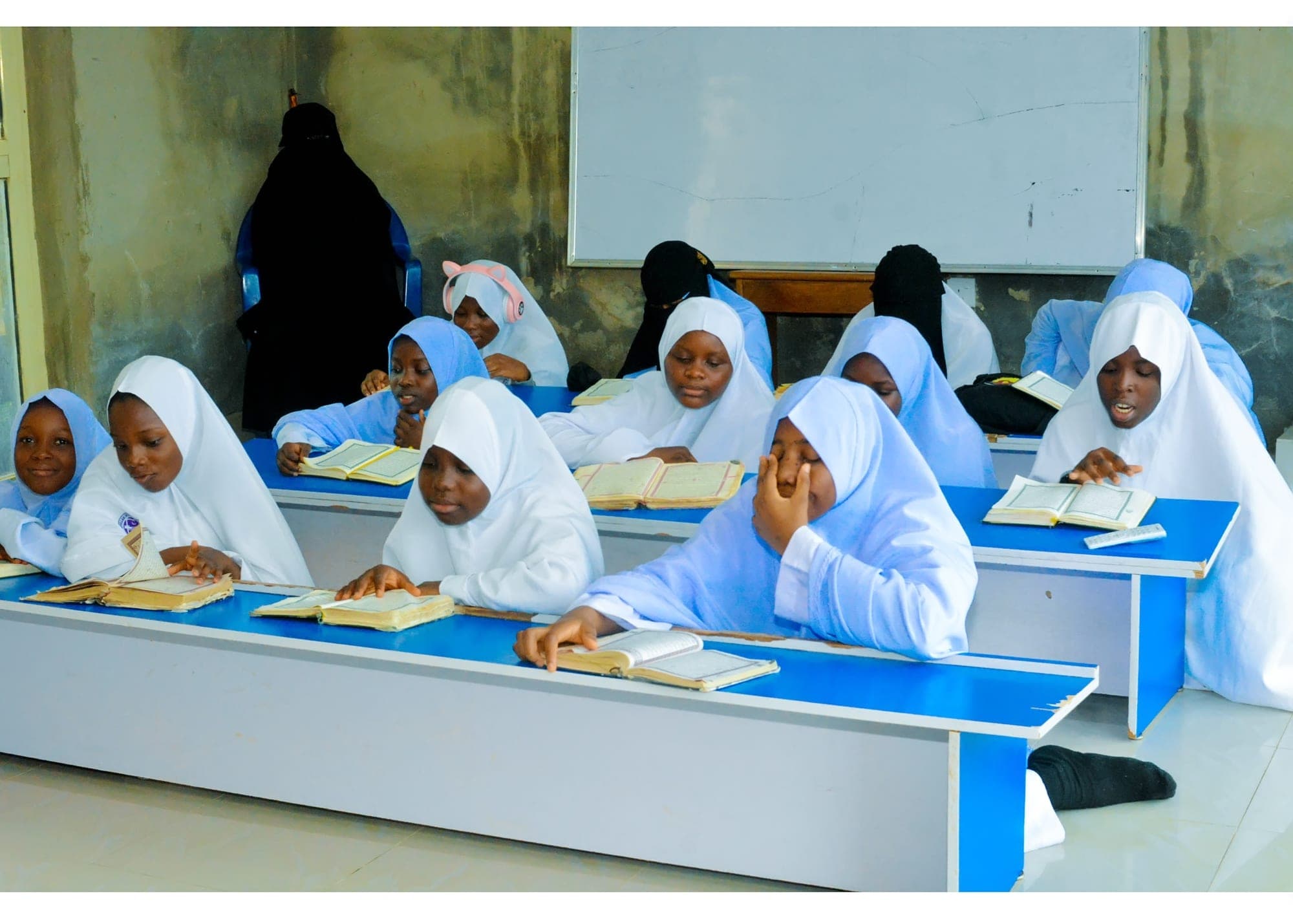 Tahfiz girls reading from their Qur’ans in a bright classroom