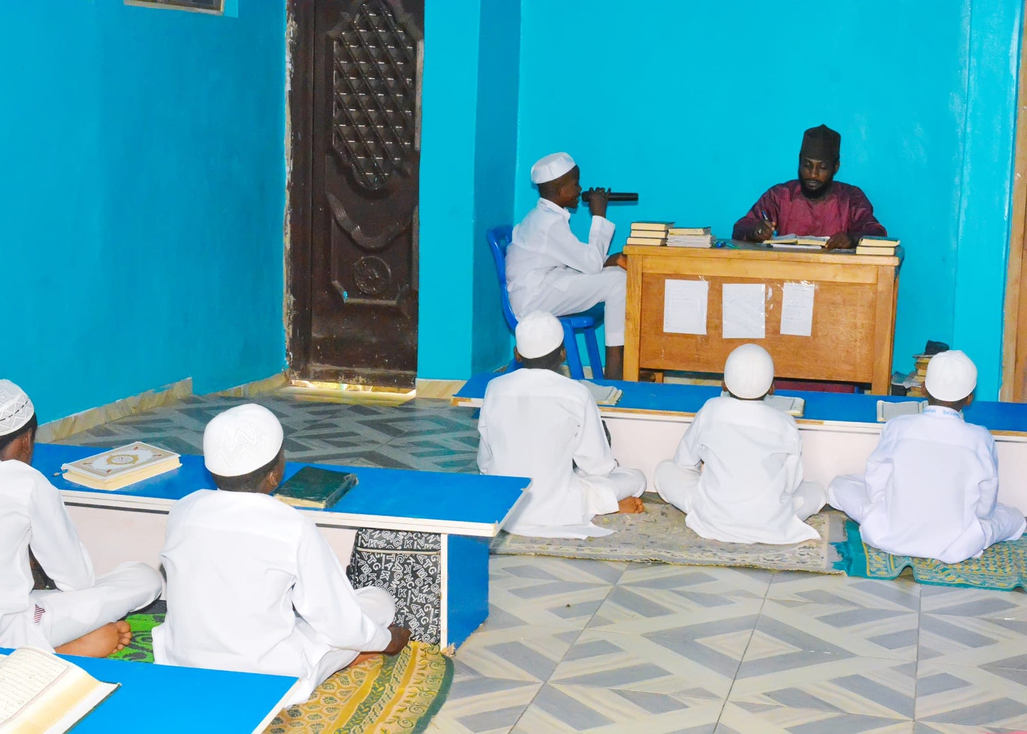 A Tahfiz student reciting before his teacher while classmates follow along